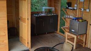 Une cuisine compacte comprenant un évier, une cuisinière et des placards, une petite table avec des chaises et un réfrigérateur.