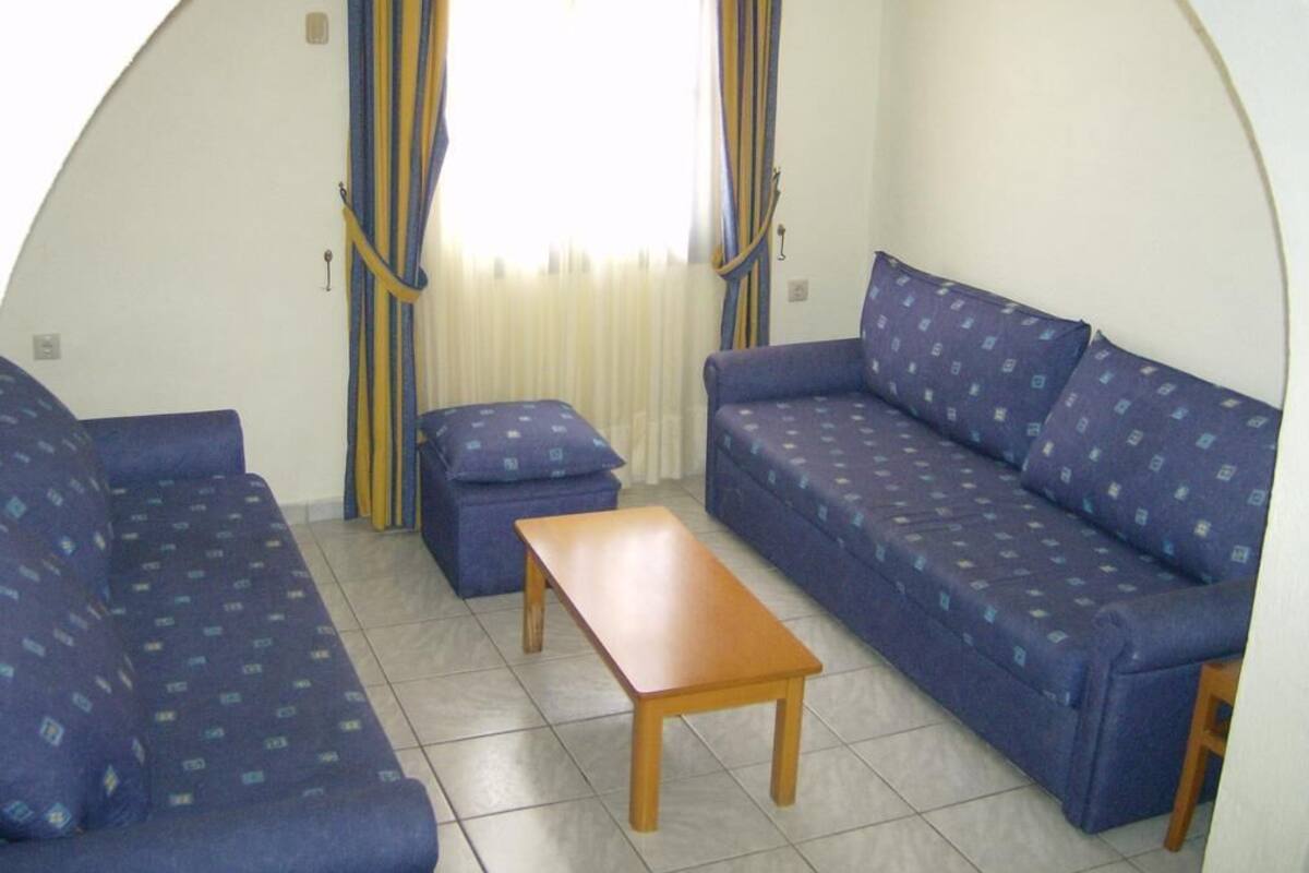 A compact living space with a sofa set, a small table, and curtains.