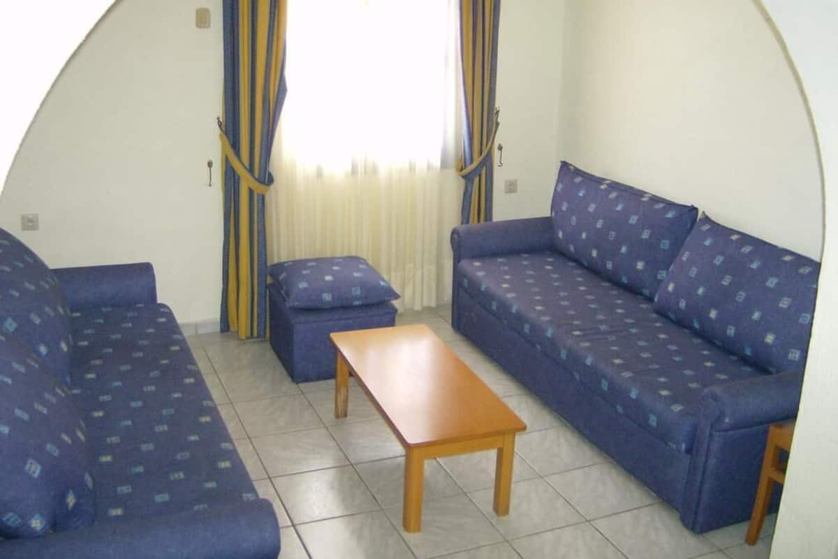 Quarto com sofá, mesa de madeira e cortinas.