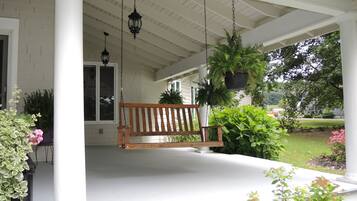 A porch with a wooden bench, hanging lanterns, and potted plants.