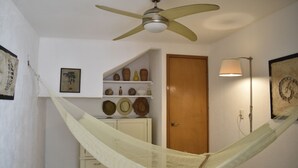 A room with a hammock, a ceiling fan, a wooden door, and shelves with decorative items. - Casa Mosha 2 La Mejor Atención, Cerca de Todo (benito juarez)