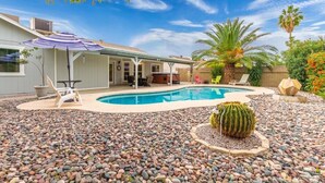 A backyard with a swimming pool, patio furniture, and a cactus.