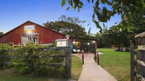A rustic barn with a glass extension, a pathway leading to a carriage, and a well-maintained garden.