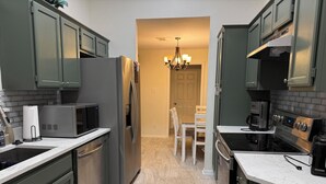 Una cucina moderna con elettrodomestici in acciaio inossidabile, un piano di lavoro in marmo e un lampadario.