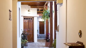 A hallway with a tiled floor, wooden beams, and potted plants. - COZY & BRIGHT APT - 5 min to Old Town (Quito)