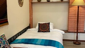 A bedroom with a bed, a nightstand, a lamp, a decorative mirror, and a brick archway. - COZY & BRIGHT APT - 5 min to Old Town (Quito)