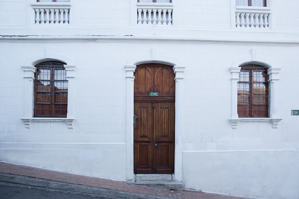 Un bâtiment blanc doté d’une grande porte double en bois et de deux fenêtres à cadre en bois.