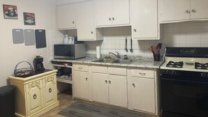 A kitchen with white cabinets, a microwave, a gas stove, and a coffee maker.