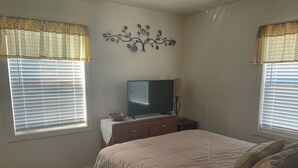 A bedroom with a bed, a TV, and a decorative wall piece.