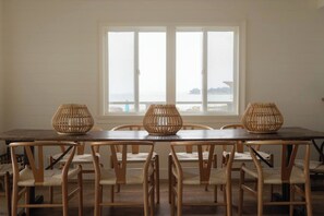 Un coin repas avec une table et des chaises en bois, une grande fenêtre offrant une belle vue et deux vases en osier posés sur la table.