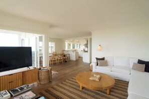 Een moderne woonkamer met een flatscreen televisie, een ronde houten salontafel en een witte bank.
