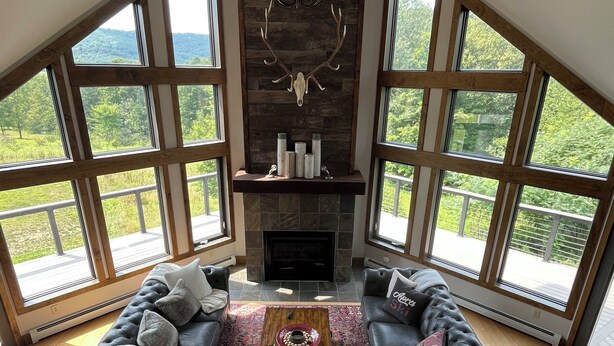 Un salón amplio con chimenea, ventanas grandes y techo alto.