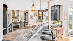 Una cocina moderna con una isla grande, taburetes de bar e iluminación colgante.