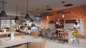 A modern restaurant with high tables and chairs, pendant lighting, and a brick accent wall.
