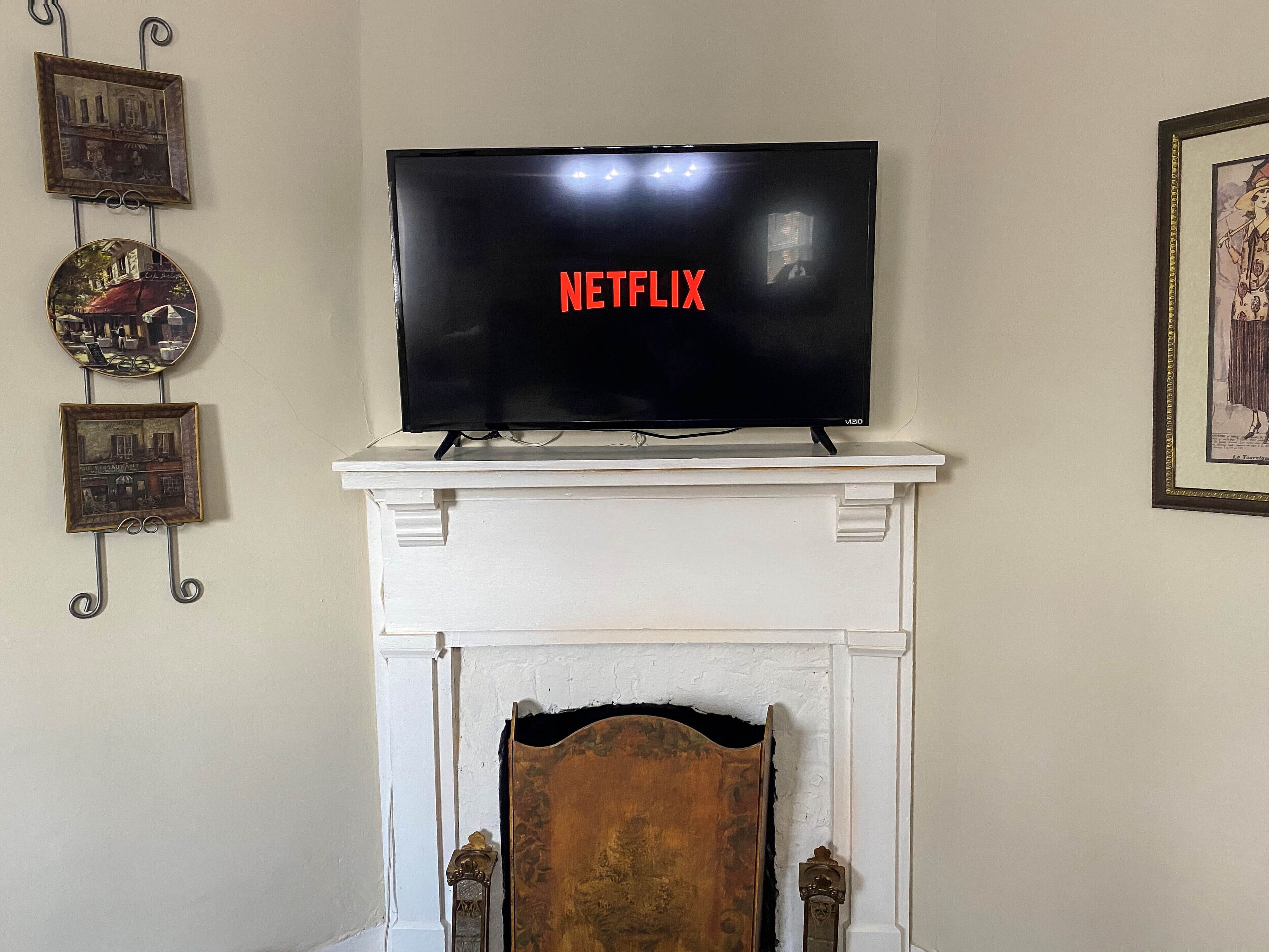 A flat-screen TV mounted on a white mantelpiece above a fireplace.