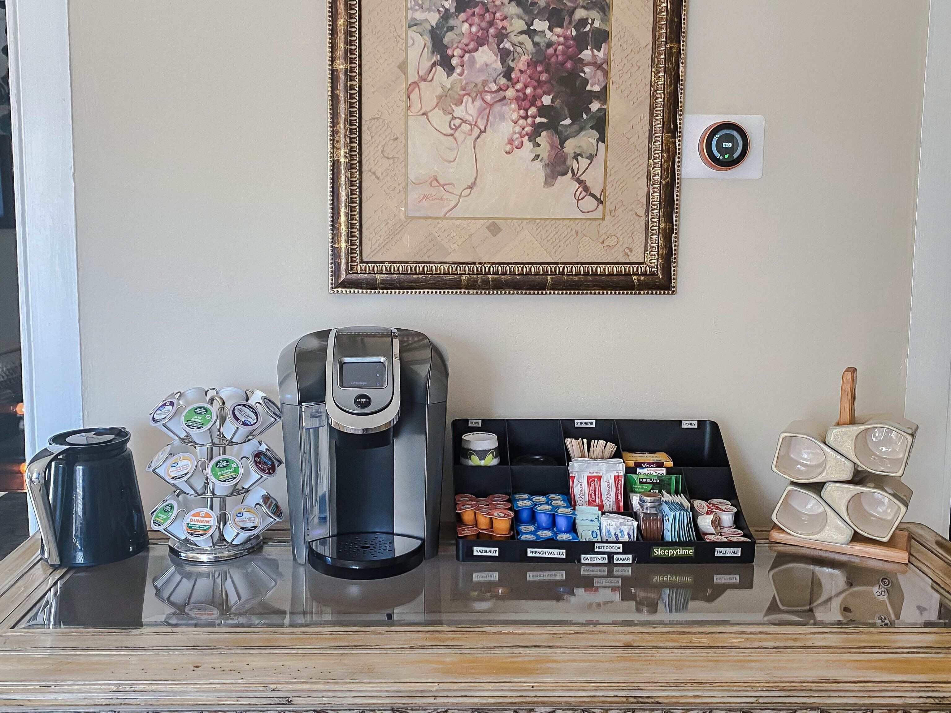 A coffee station with a coffee maker, a selection of coffee pods, and a display of tea and coffee products.