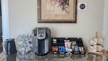 A coffee station with a coffee maker, a selection of coffee pods, and a display of tea and coffee products.