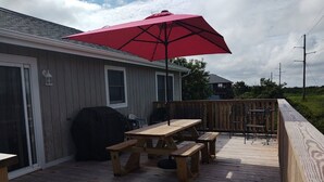 A wooden deck with a picnic table and chairs, a barbecue grill, and a red umbrella. - 3 MIN. WALK TO THE BEACH!  South Nags Head  (Nags Head)