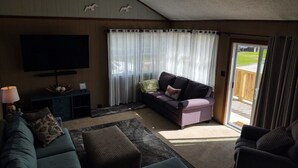A living room with a sofa, a television, and a sliding glass door leading to an outdoor area. - 3 MIN. WALK TO THE BEACH!  South Nags Head  (Nags Head)