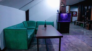 A living room with a green sofa, a small table, and a television. - Super OYO 3728 Tunas Plaza Residence (Bekasi)