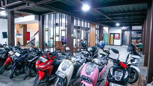A row of parked scooters in an indoor parking area with a visible staircase leading to an upper level. - Super OYO 3728 Tunas Plaza Residence (Bekasi)