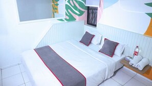 A modern hotel room with a bed, pillows, a bedside table with a bottle, and a window with a view. - Super OYO 3728 Tunas Plaza Residence (Bekasi)