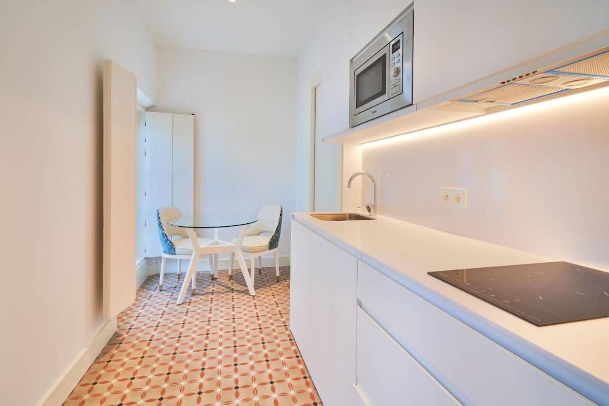 A compact kitchen with a microwave, a sink, and a dining area with two chairs.