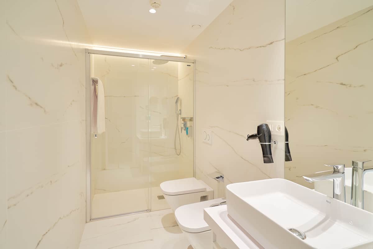 A modern bathroom with a glass-enclosed shower, a white toilet, and a large white sink.