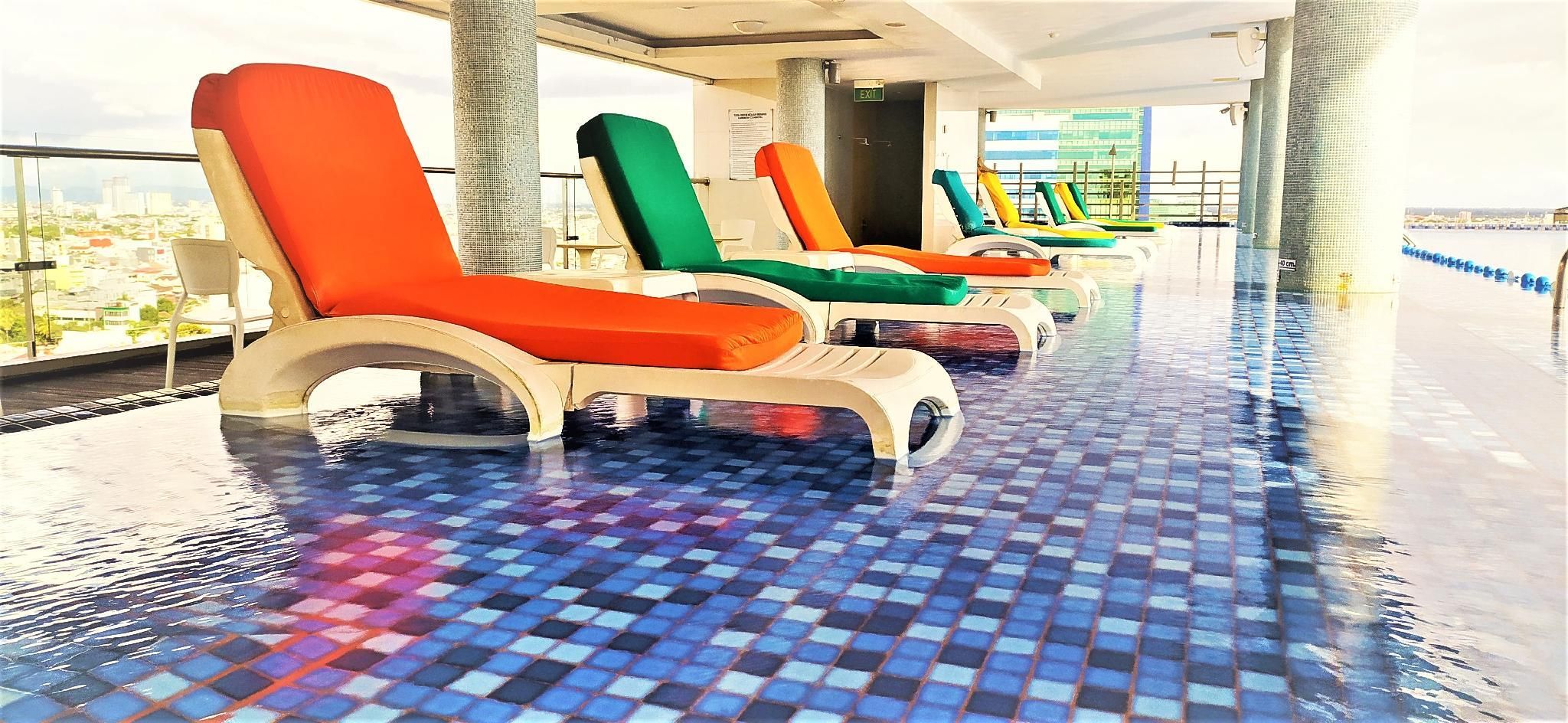 A poolside area with lounge chairs and a tiled floor.