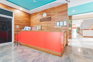 A reception desk with a wooden wall and a clock above it, labeled "BUDAYA". - Sans Hotel Budaya Cirebon (Kesambi)