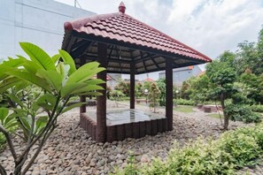 A gazebo with a tiled roof, surrounded by gravel and greenery. - Sans Hotel Budaya Cirebon (Kesambi)