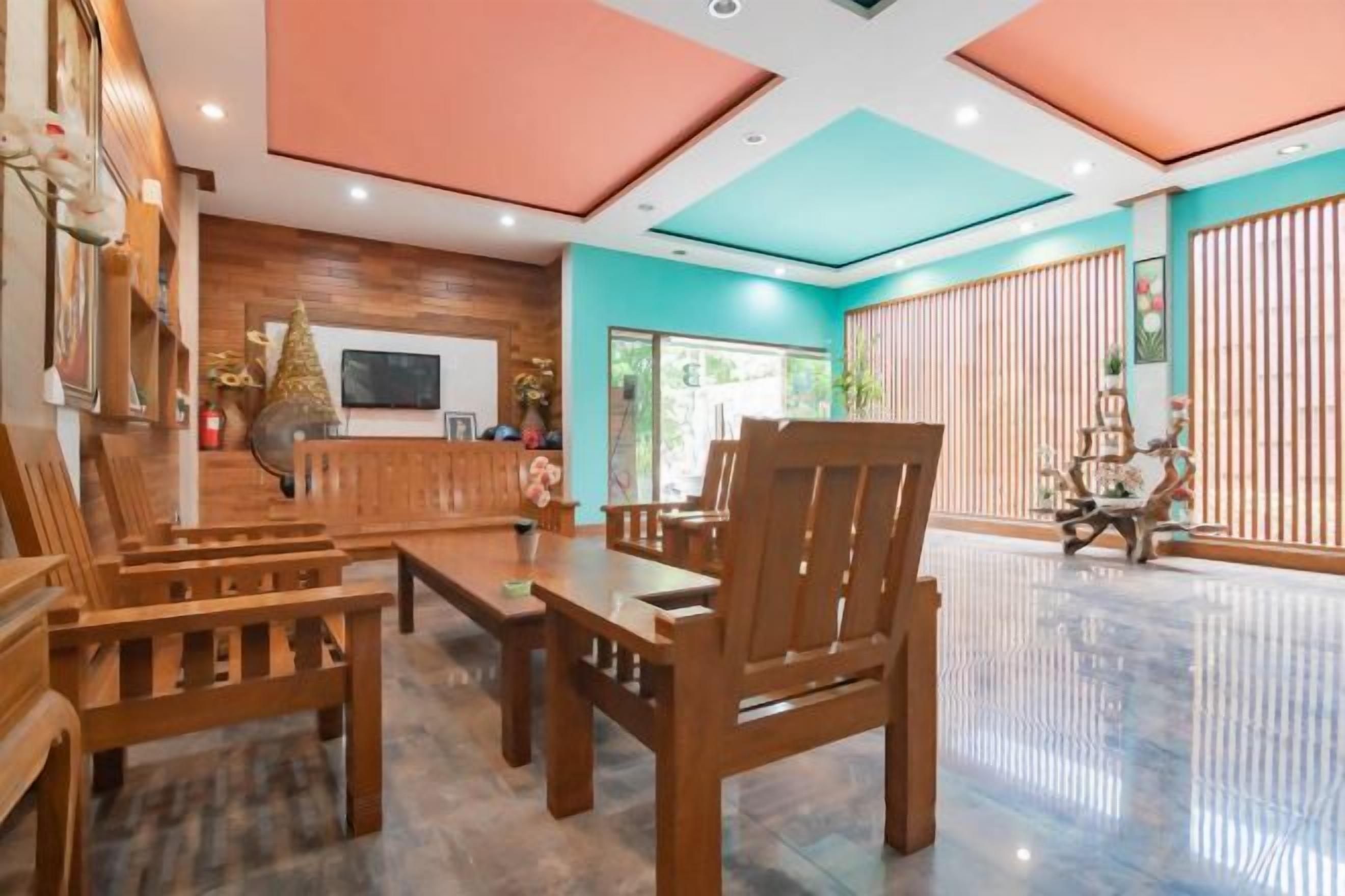 A hotel lobby with wooden furniture, a reception desk, and a large window.