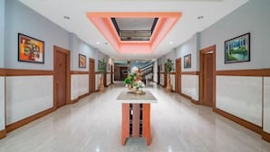 A hotel hallway with a central table, framed artwork on the walls, and a skylight.