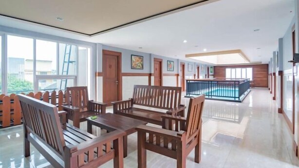A spacious indoor area with wooden furniture, large windows, and a pool area.