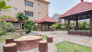 A courtyard with a circular seating area, a gazebo, and a building with a red roof.
