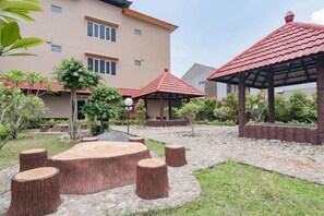 Un patio con una zona de estar circular, un pabellón y un edificio con techo rojo.