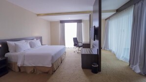 A hotel room with a bed, a desk, a chair, a television, and curtains. - Labersa Toba Hotel and Convention Centre Balige (Balige)