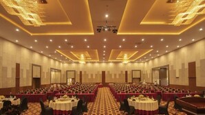 A conference room with rows of tables and chairs, a carpeted floor, and a stage at the front. - Labersa Toba Hotel and Convention Centre Balige (Balige)