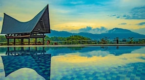 A pool with a checkered pattern, a covered seating area, and a mountainous backdrop.