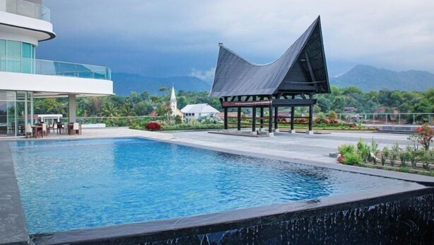 A swimming pool with a modern building and a pavilion in the background. - Labersa Toba Hotel and Convention Centre Balige (Balige)