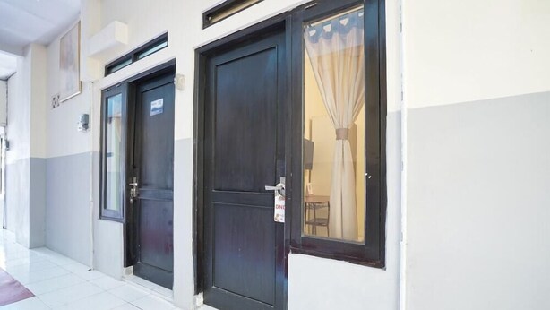 A row of dark-colored doors with a sign indicating 'DND' on the right door. - Hotel O Seturan Near Hartono Mall Yogyakarta Formerly Maleo Kostel (Depok)