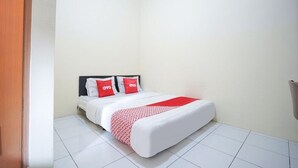 A neatly made bed with a white and red bedspread, two pillows with 'OYO' branding, and a white headboard in a corner room with white walls and tiled flooring. - Hotel O Seturan Near Hartono Mall Yogyakarta Formerly Maleo Kostel (Depok)