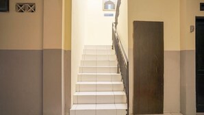 A staircase with white steps and a black railing, leading to a dark door. - Hotel O Seturan Near Hartono Mall Yogyakarta Formerly Maleo Kostel (Depok)