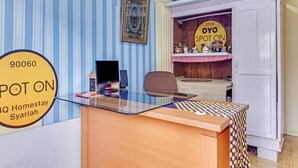 Une pièce comprenant un bureau, un ordinateur et une chaise. Il y a un panneau accroché au mur et un meuble sur lequel sont posés divers objets.