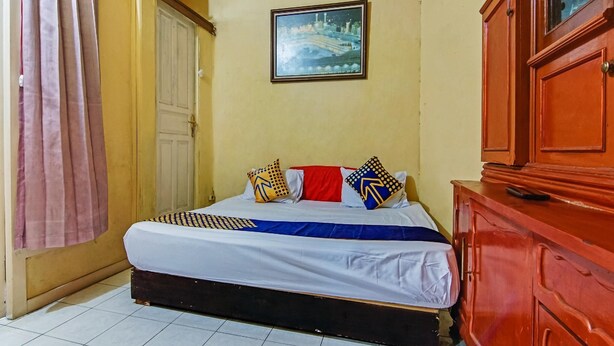 Een slaapkamer met een bed, een kledingkast, een foto aan de muur en een gordijn.