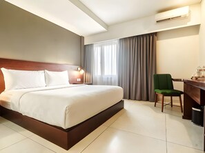 Een hotelkamer met een bed, een bureau, een stoel en een airconditioning.