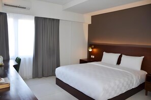 Een hotelkamer met een groot bed, een bureau en een stoel.