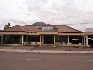Un edificio con techo de tejas, un cartel que dice 'Hotel Grand Wisata' y una entrada visible.