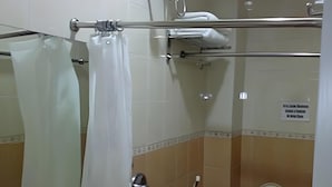 Une salle de bain avec un rideau de douche, un porte-serviettes, des toilettes et un panneau accroché au mur.