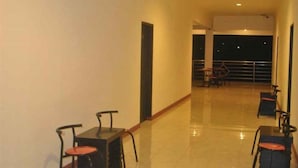 Un couloir avec des tables et des chaises, qui mène à un espace balcon.